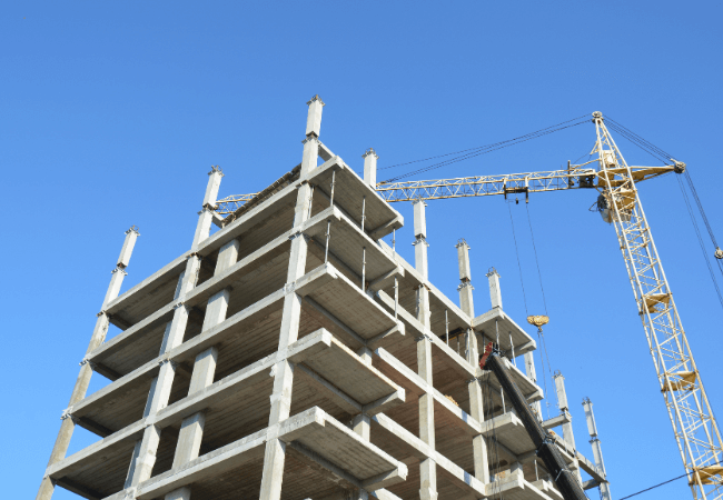 High-rise office building under construction with crane against clear blue sky